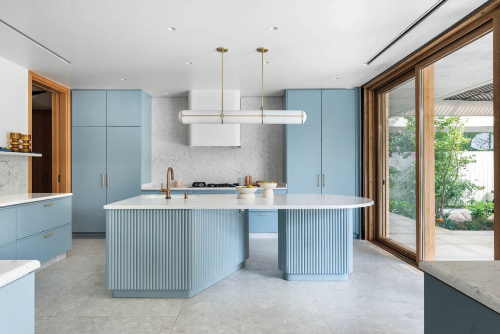 a light blue kitchen island white a white pendant light above