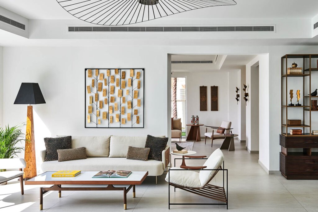 a living room with white walls and a cream couch with gray pillows