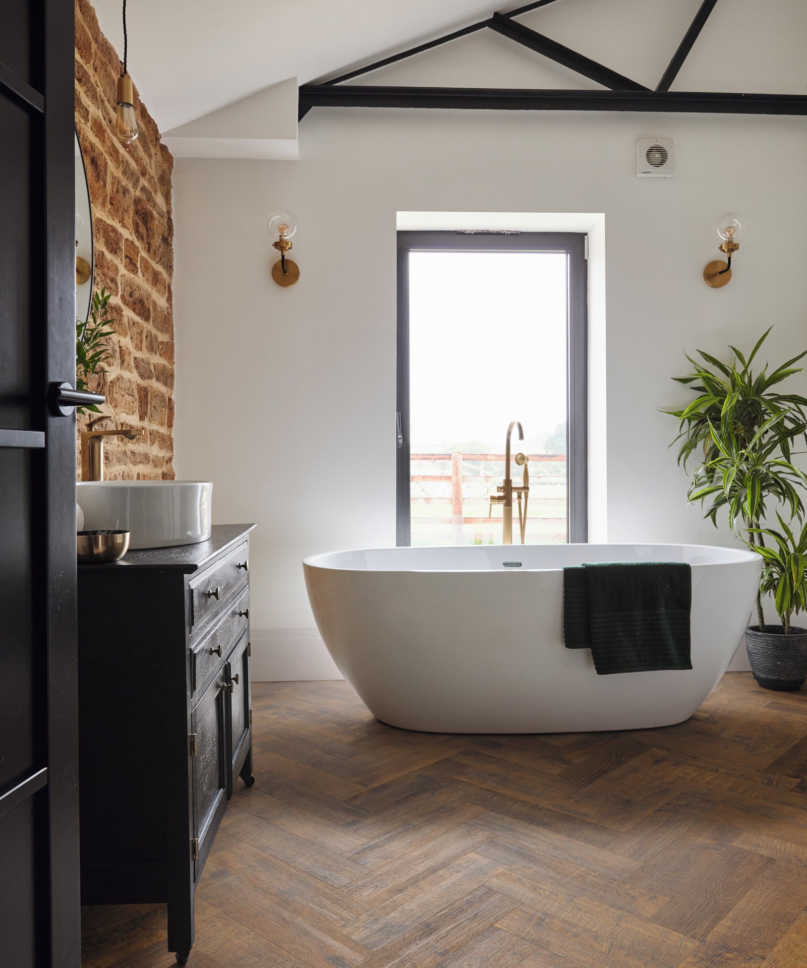 Karndean flooring walnut effect wooden flooring vinyl planks in bathroom with white freestanding bath in front of window