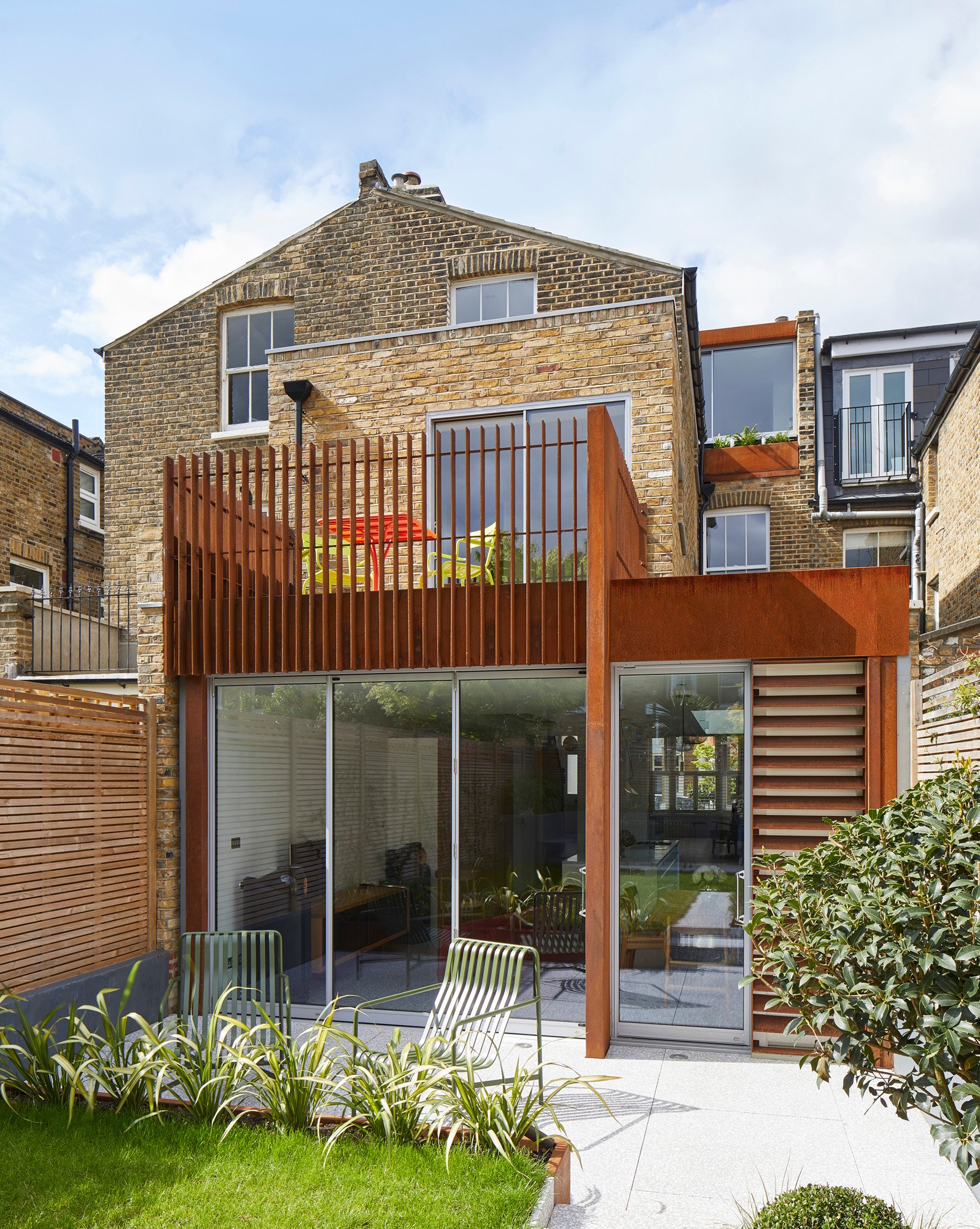 a corten wrap around kitchen extension with a balcony