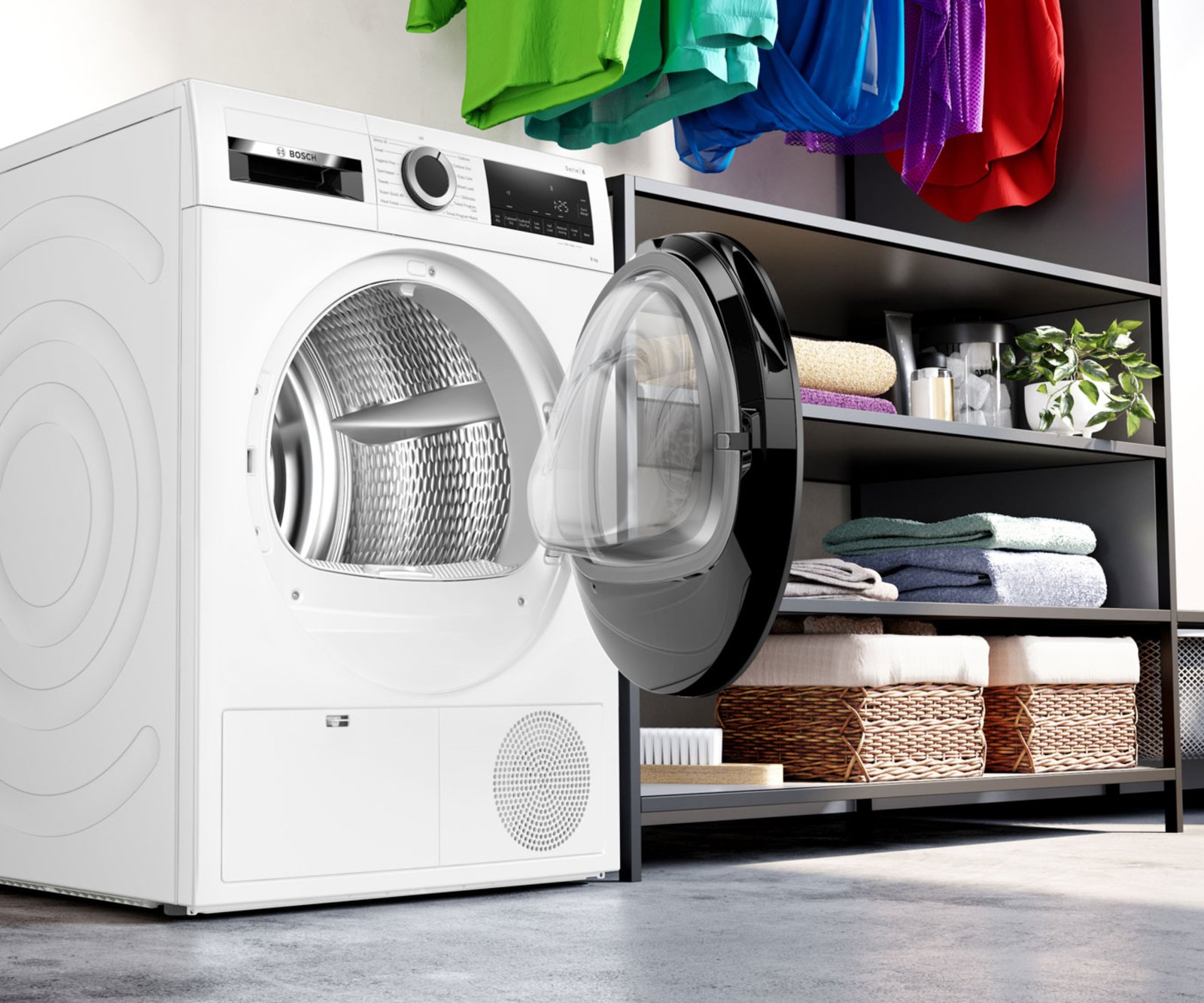 tumble dryer with door open in utility type rom with colourful clothing hanging
