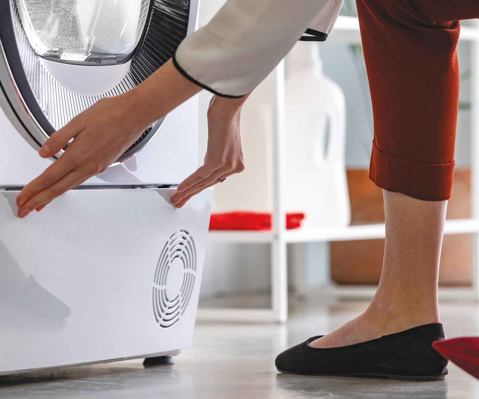close up shot of base of tumble dryer with woman's hands opening bottom vent