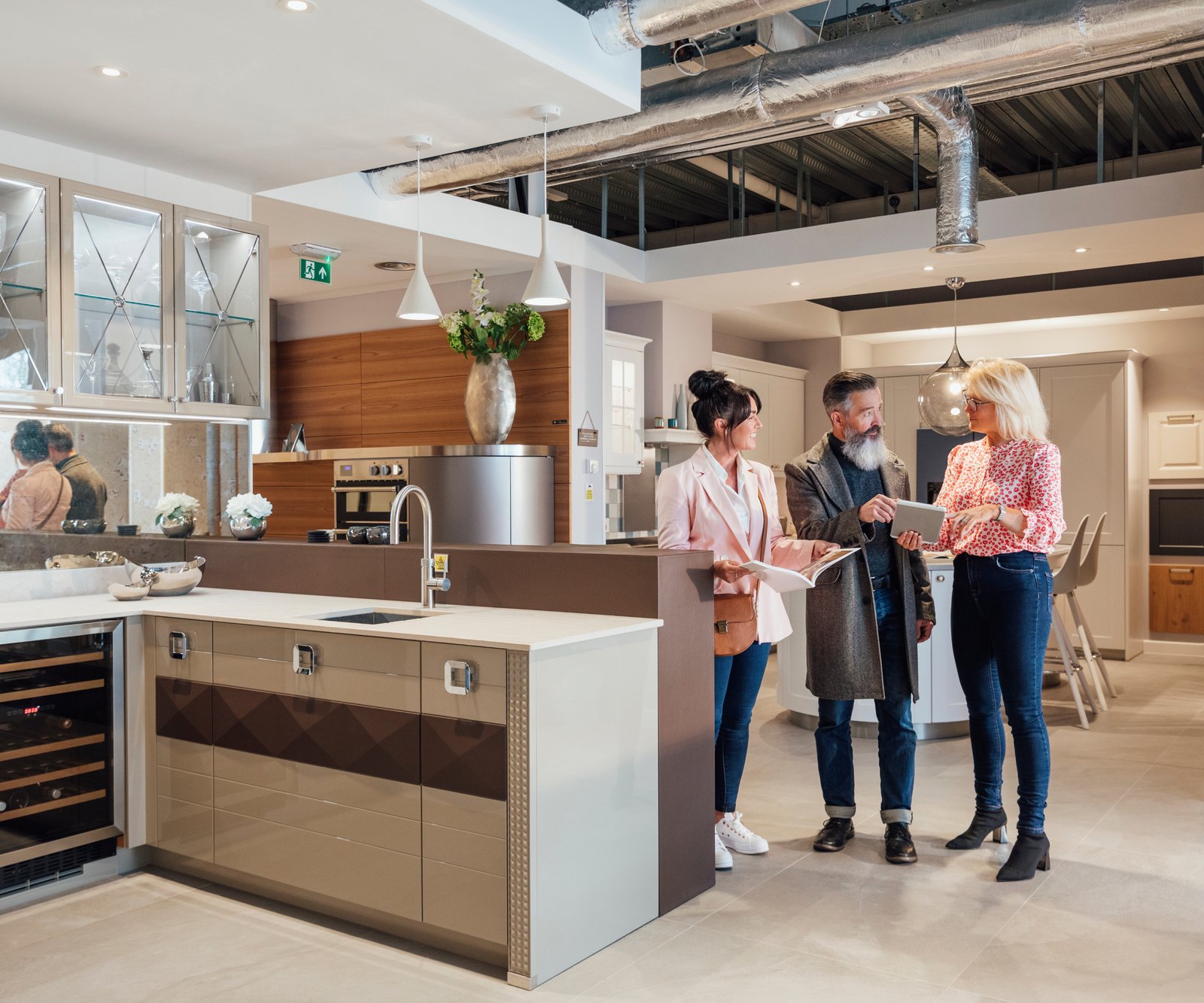 male and female couple in kitchen showroom talking to saleswoman