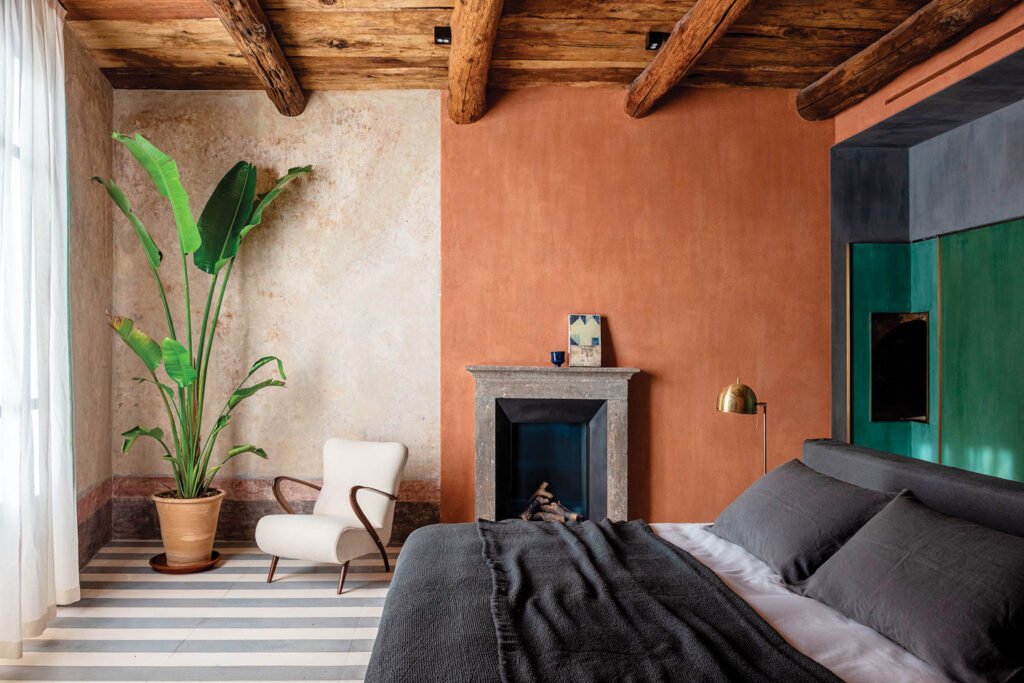 bedroom with tan and white walls, wooden beamed ceiling and plant in corner