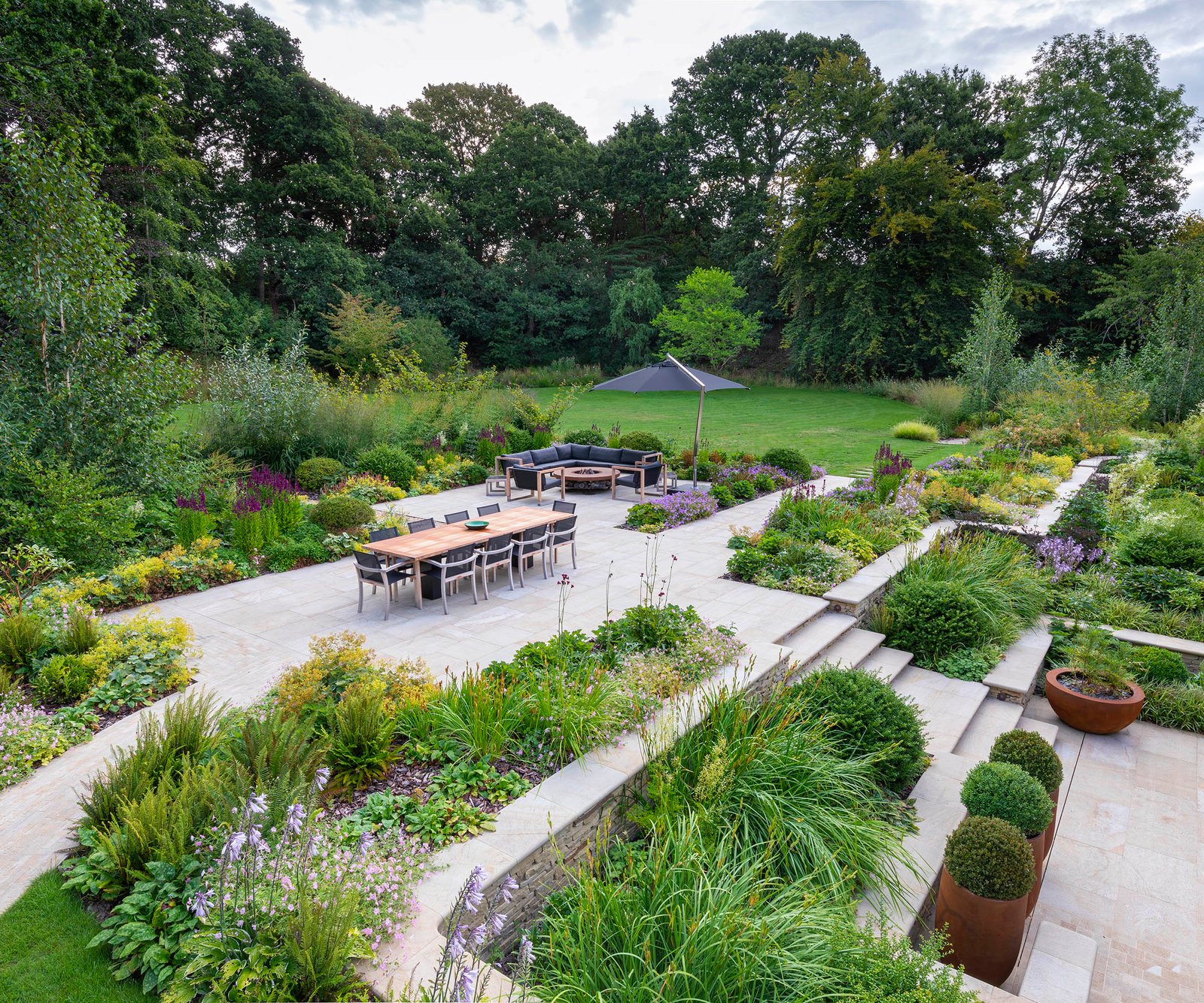 A beautifully landscaped garden with tiered planting beds and seating area