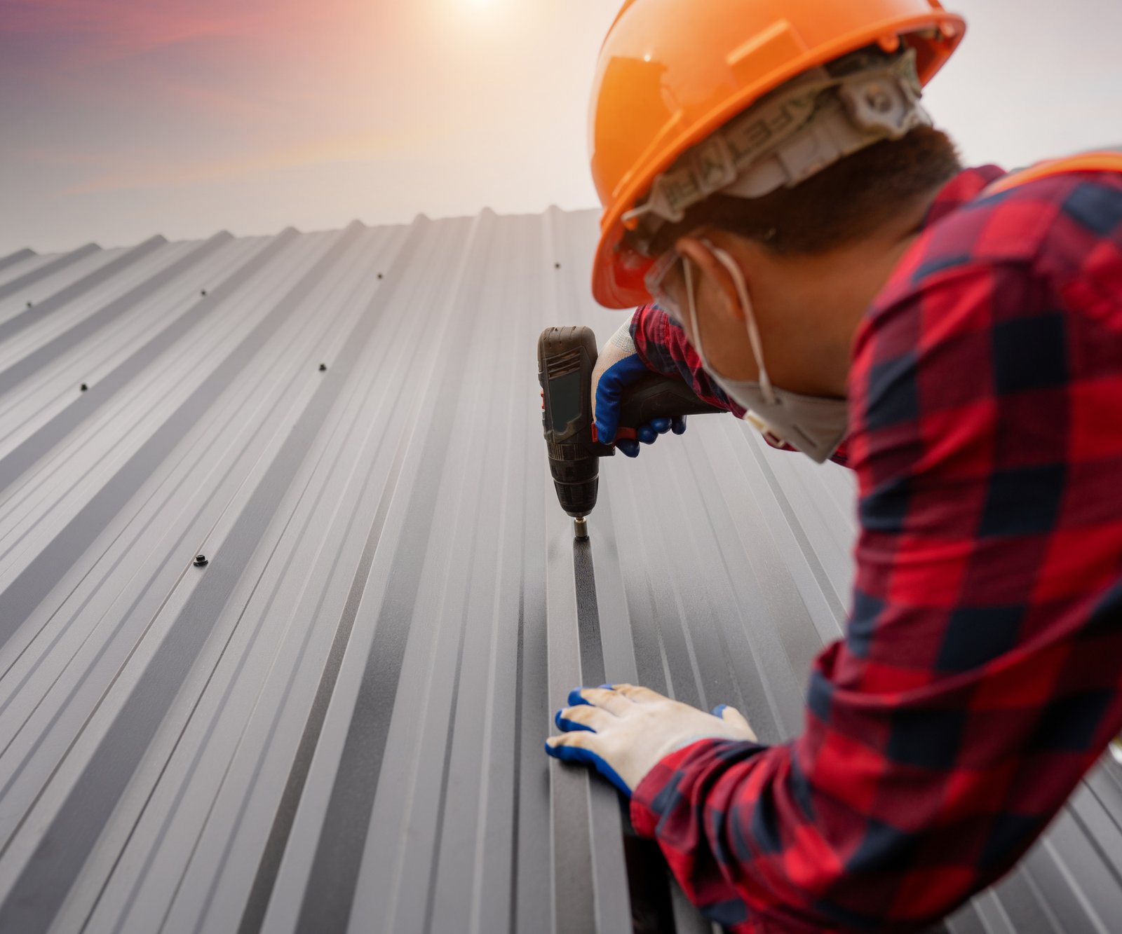 man drilling corrugated metal roof section